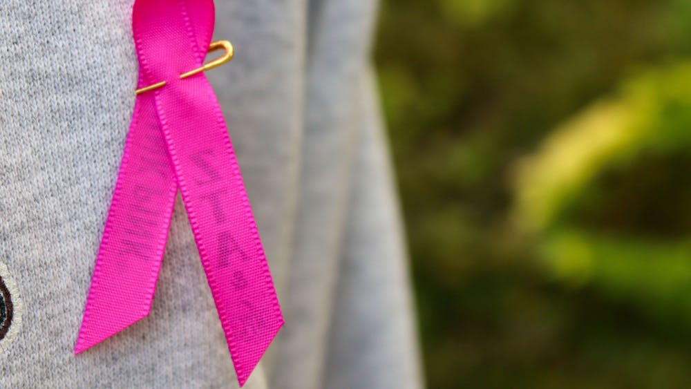 A breast cancer awareness ribbon is pinned to a woman&#x27;s shirt Oct. 21, 2021. IU School of Medicine researcher Dr. Bryan Schneider is leading a new nationwide clinical trial to improve cure rates for patients with triple-negative breast cancer.
