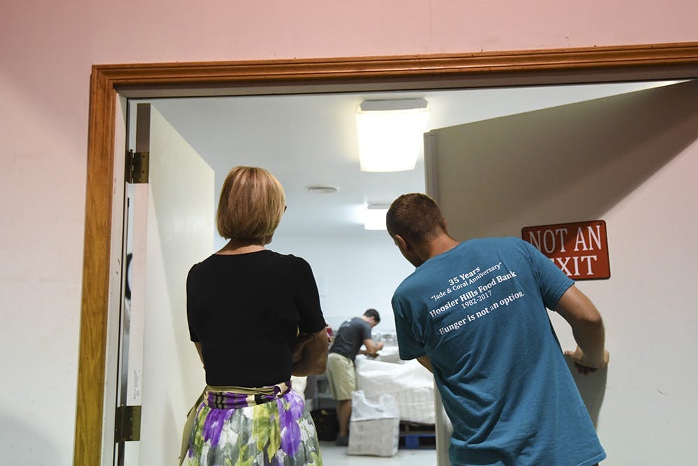 IU intern Ryan Mccauley leads Suzanne Crouch into a cold room where volunteers bag potatoes. The Hoosier Hills Food Bank has 2,000 volunteers per year.