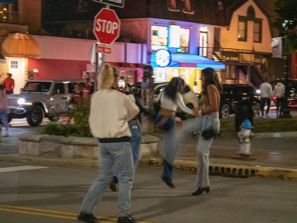 A group of women dance along a closed Kirkwood Avenue after exiting Kilroys on Kirkwood, one of the most popular bars in Bloomington. At just after 9 p.m., the bars are filling up by the minute as lines stretching around the side of the building continue to grow longer.