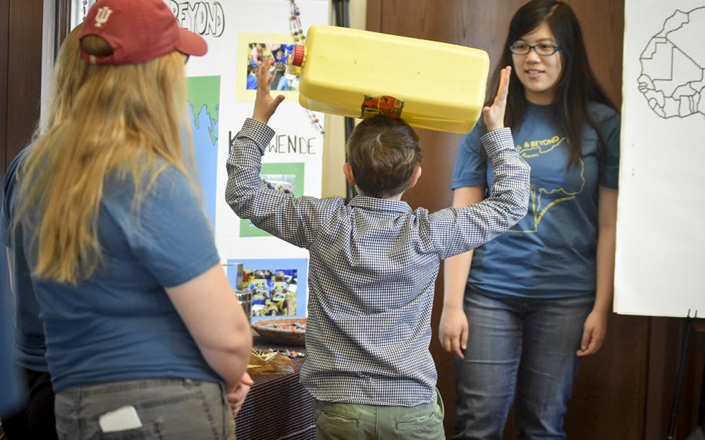 IU students and Bloomington residents view artifacts and photos from Rwanda while trying their hand at the ancient practice of "carrying on the head" during the Visions of Rwanda event Tuesday evening in the Hutton Honors College. 