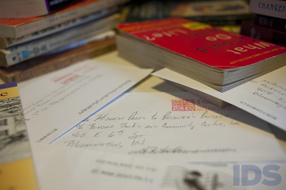 Letters from volunteers to prisoners sit amongst books in Boxcar Books. The letters and books are sent to prisons as part of the Midwest Pages to Prisoners Project.