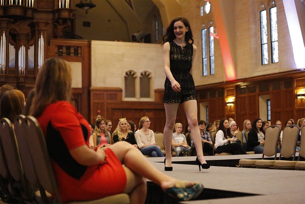 Junior Sydney King struts down the runway while America's Next Top Model winner, Whitey Thompson, right, watches from the audience during the "Love the Skin You're In" fashion show Tuesday at Alumni Hall in the IMU. Thompson spoke after the fashion show about body positivity.