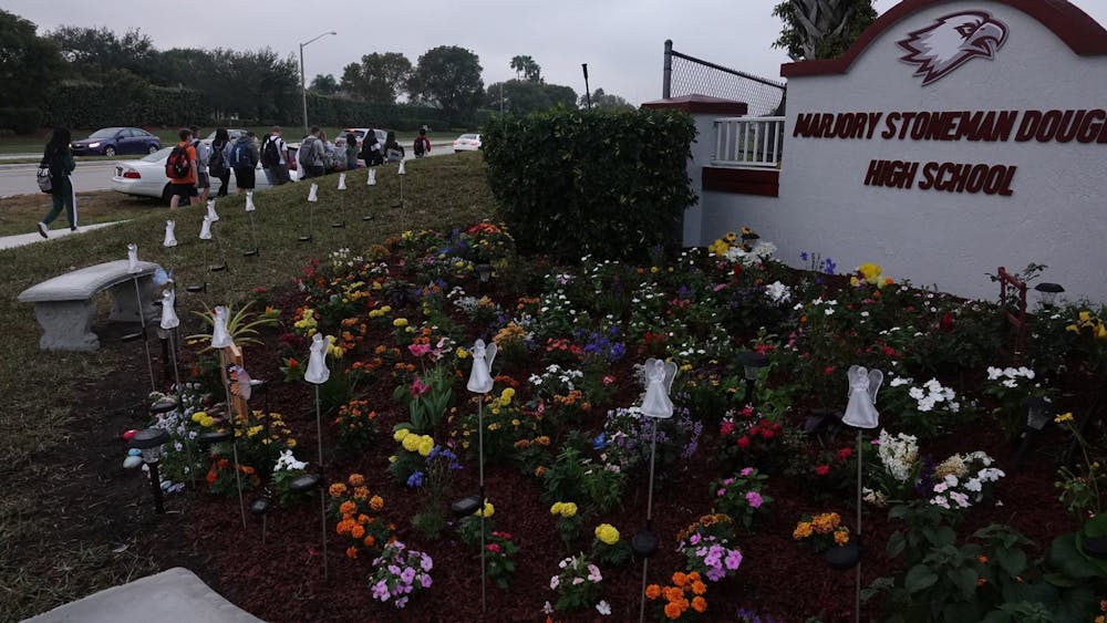 Students walk past the memorial garden outside of Marjory Stoneman Douglas High School in Parkland, Florida. 
