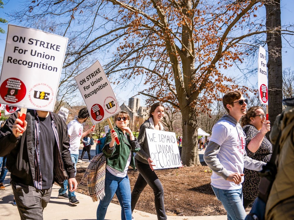 Protestors march through campus April 14, 2022. The College of Arts and Sciences will reduce compensation and cut health care for its graduate workers starting in fall 2023.