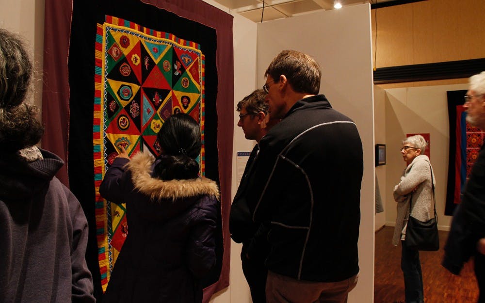 During the opening of the&nbsp;"Quilts of Southwest China" attendees stop to take a look at the many quilts in the Mathers Museum with curator Lijun Zhang.&nbsp;