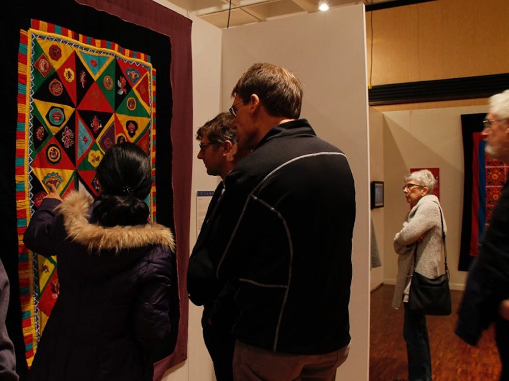 During the opening of the&nbsp;"Quilts of Southwest China" attendees stop to take a look at the many quilts in the Mathers Museum with curator Lijun Zhang.&nbsp;
