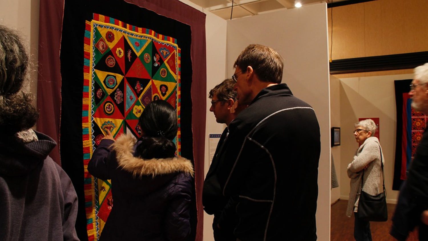 During the opening of the&nbsp;"Quilts of Southwest China" attendees stop to take a look at the many quilts in the Mathers Museum with curator Lijun Zhang.&nbsp;
