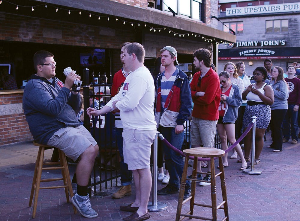 Freshman Nick Musulin checks ID's outside the front door of Kilroy's on Kirkwood on Tuesday.  The front door line wrapped around the corner of Kirkwood and Dunn.