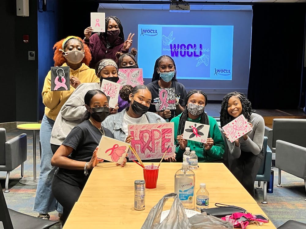 Members of the Women of Color Leadership Institute pose for a picture at during its &quot;Paint like Picasso&quot; event on Oct. 26, 2021, at the Read Hoosier Den. Event organizer and IU junior Anaijah Dunn directed attendees to paint breast cancer-themed butterflies.
