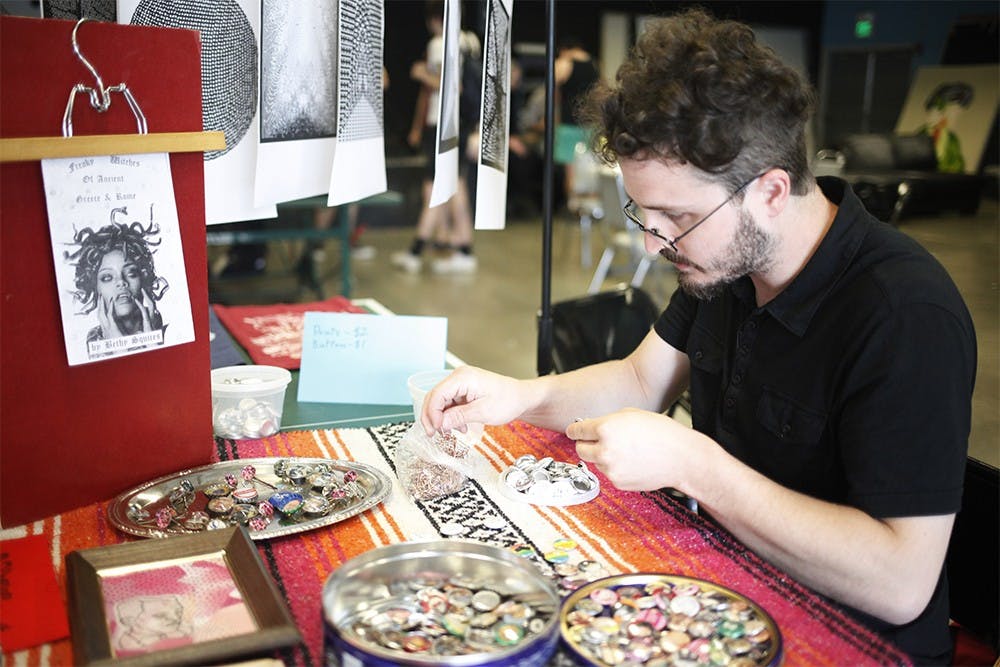 Colin Jenkins makes buttons at the Affordable Art Fair in Rhino's Youth Center on Sunday.  "We just got a button maker so we've been going crazy with them," he said.  The fair featured handmade art and drawings, and was held in conjunction with Chaos Fest.