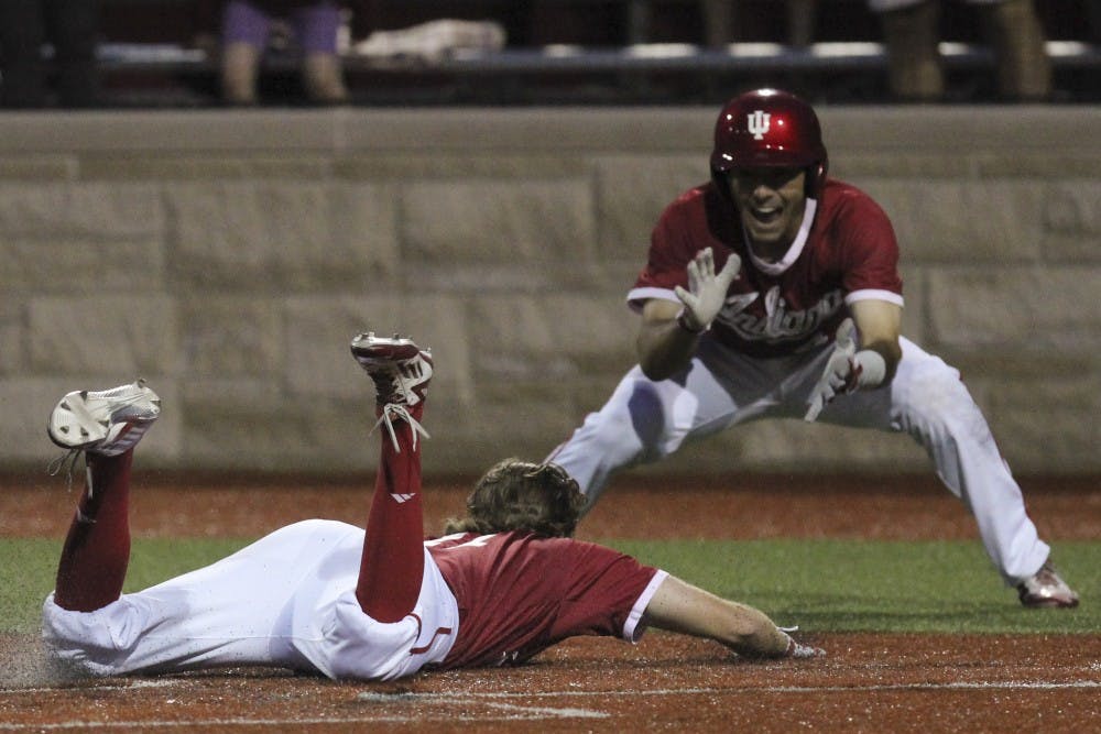 Junior second baseman Tony Butler cheers as senior shortstop Brian Wilhite slides into home in the second game against Northwestern Apr. 29, 2016. IU came from behind in the last two innings to win 4-3 