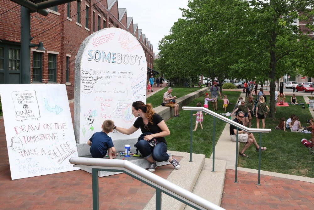 <p>People gather to write on a prop tombstone as part of Granfalloon: A Kurt Vonnegut Convergence on Saturday, May 12, at City Hall. The festival featured musical guests as well as panels to discuss Vonnegut's works.&nbsp;</p>