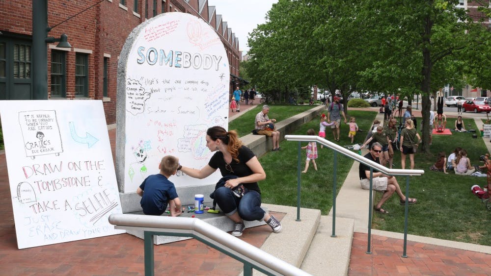 People gather to write on a prop tombstone as part of Granfalloon: A Kurt Vonnegut Convergence on Saturday, May 12, at City Hall. The festival featured musical guests as well as panels to discuss Vonnegut's works.&nbsp;