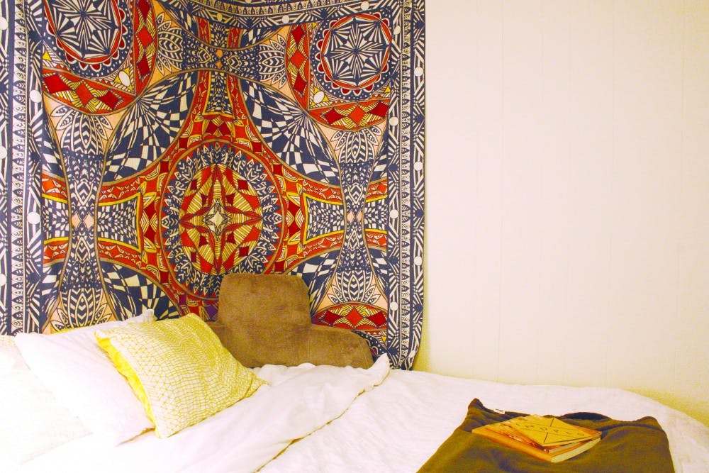 Say no to blank walls: A tapestry is tucked in the corner of Emily's room as a quasi-backboard to the bed. Tapestries can be a centerpiece of a room and add color and warmth. 