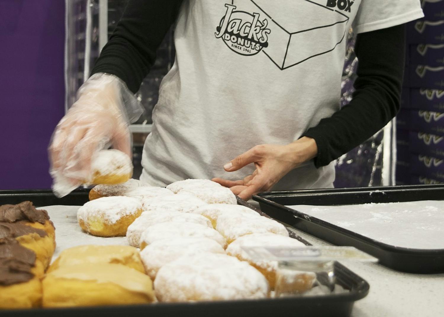 Jack's Donuts team member Jackie Willett transfers doughnuts to a tray in Jack's Donuts' Bloomington location on College Mall Road. Jack's Donuts, which originally opened in New Castle, Indiana, serves coffee and donuts.
