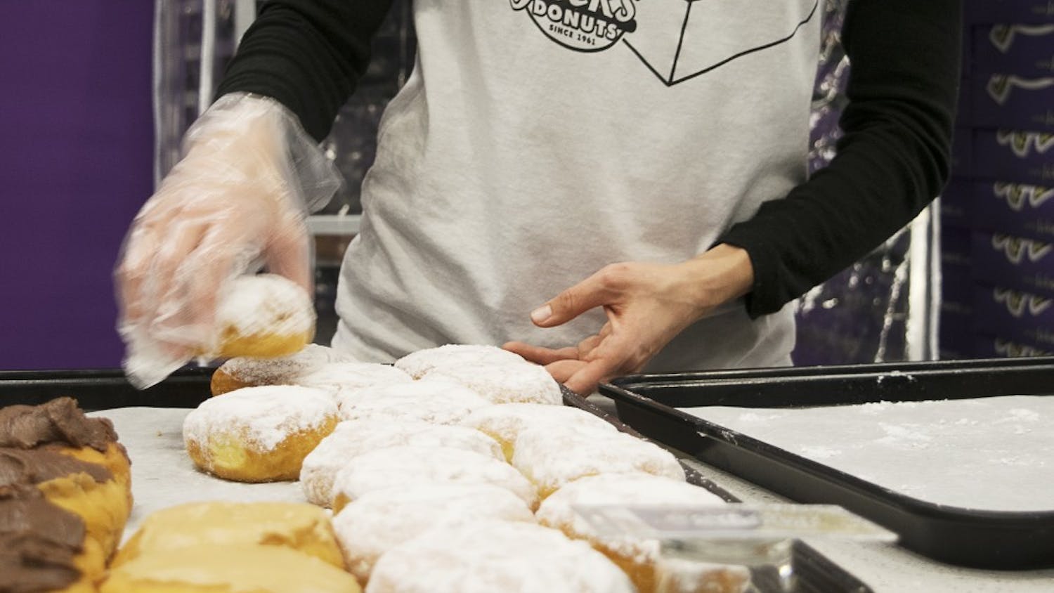 Jack's Donuts team member Jackie Willett transfers doughnuts to a tray in Jack's Donuts' Bloomington location on College Mall Road. Jack's Donuts, which originally opened in New Castle, Indiana, serves coffee and donuts.