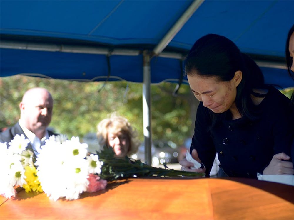 Yan Li, Yaolin Wang's cousin, holds Jielin Wang, Wang's sister, in front of Yaolin's casket before it went underground during the burial service on Oct.11.  Jielin was the last one to leave after the casket was in the ground.