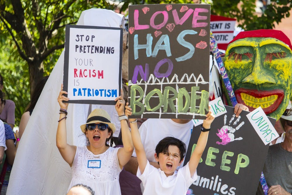 <p>A woman and child hold up signs while chanting during the #FamiliesBelongTogether rally Saturday morning outside the Monroe County Courthouse. The event was organized by the Families Belong Together Coalition and took place nationwide and featured over 600 rallies, including one in Indianapolis.&nbsp;</p>