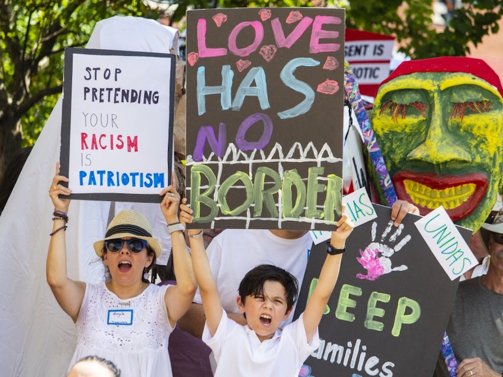 A woman and child hold up signs while chanting during the #FamiliesBelongTogether rally Saturday morning outside the Monroe County Courthouse. The event was organized by the Families Belong Together Coalition and took place nationwide and featured over 600 rallies, including one in Indianapolis.&nbsp;