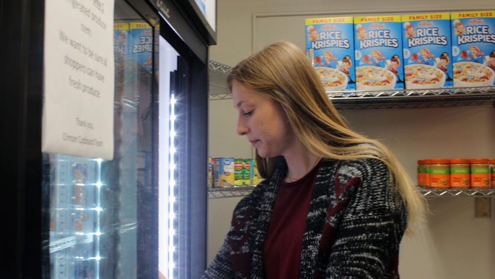 Hayley Jackson stocks the fridge on Feb. 3, 2023, at the Crimson Cupboard located inside the Campus View Apartments. The Crimson Cupboard is available for anyone who registers to use it. 