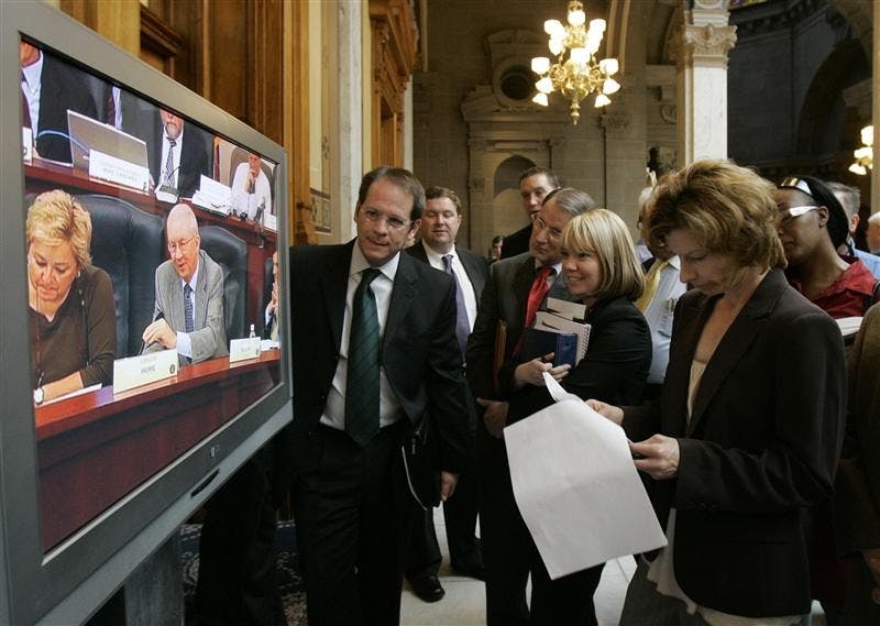 An overflow crowd listens and watches a Senate committee hearing from outside the room at the Statehouse on Thursday afternoon in Indianapolis. The committee was listening to a proposal to double state alcohol taxes to help fund the agency struggling to operate the major Indianapolis sports stadiums.