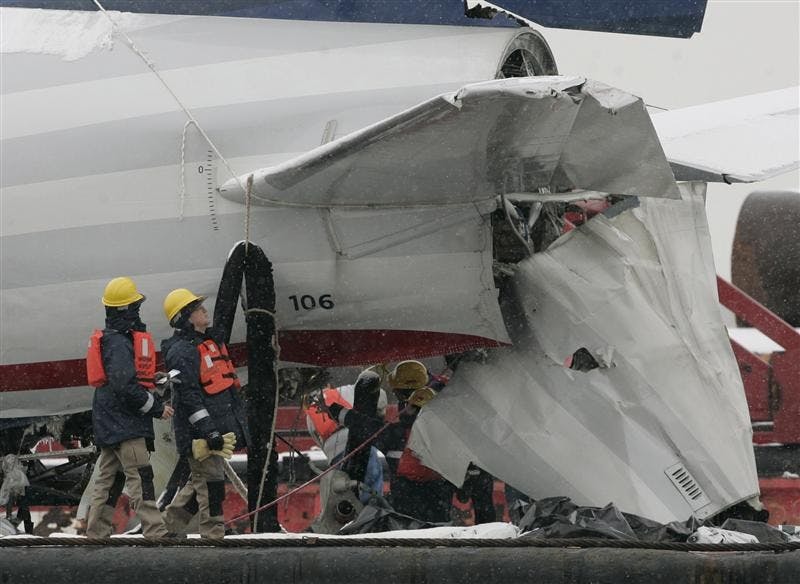 NTSB inspectors examine the tail section of US Airways Flight 1549 as it sits on a barge Monday at Weeks Marina in Jersey City, N.J. The jet was moved Sunday night from a seawall at the southern tip of Manhattan where it was lifted out of the icy Hudson River. 