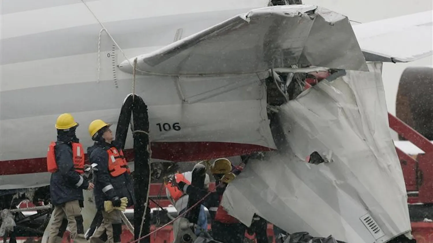 NTSB inspectors examine the tail section of US Airways Flight 1549 as it sits on a barge Monday at Weeks Marina in Jersey City, N.J. The jet was moved Sunday night from a seawall at the southern tip of Manhattan where it was lifted out of the icy Hudson River.
