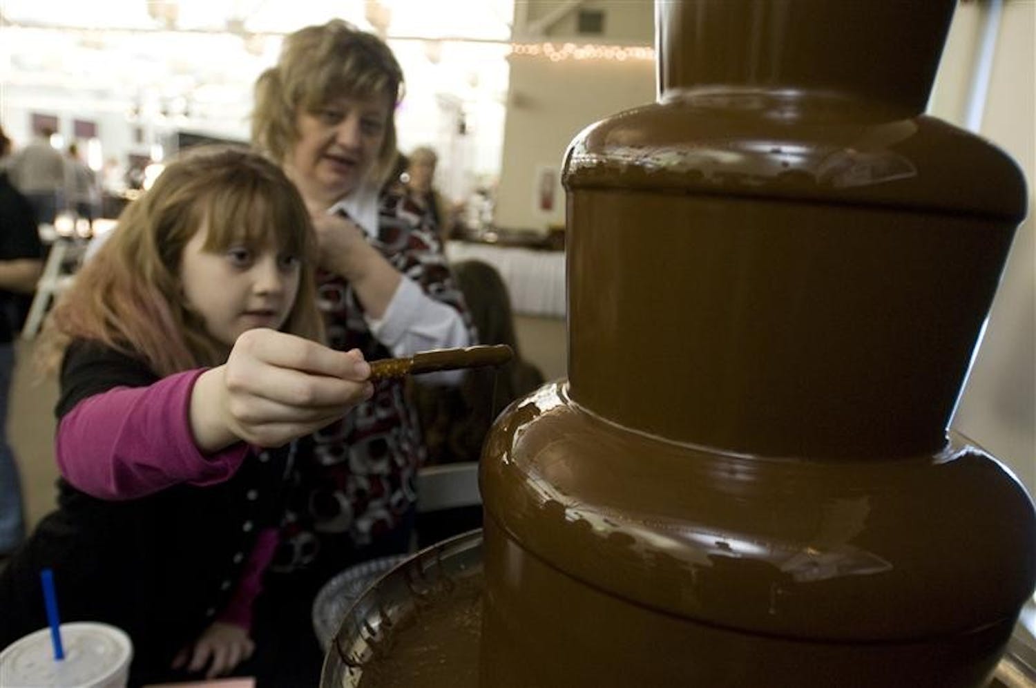 Katherine, 9, and Tina Lampke enjoy a chocolate fountain Sunday afternoon at the Bloomington Bridal Show in the Bloomington Convention Center.