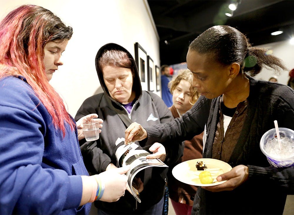 Shelby Tatum, left, Dawn, Darla, and Amelia Dixon find out which page their photos are published on Bloom Magazine Friday at Pictura Gallery. Shelby Tatum, Darla, and Dixon participated in "What Does Bloomington Look Like To Me," a photo project taken by eleven homless people along with Bloom Magazine. 
