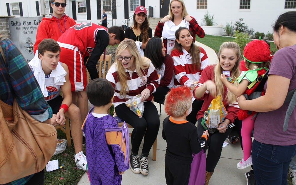 Students pass out candy to children in front of the Delta Tau Delta fraternity house on Wednesday.