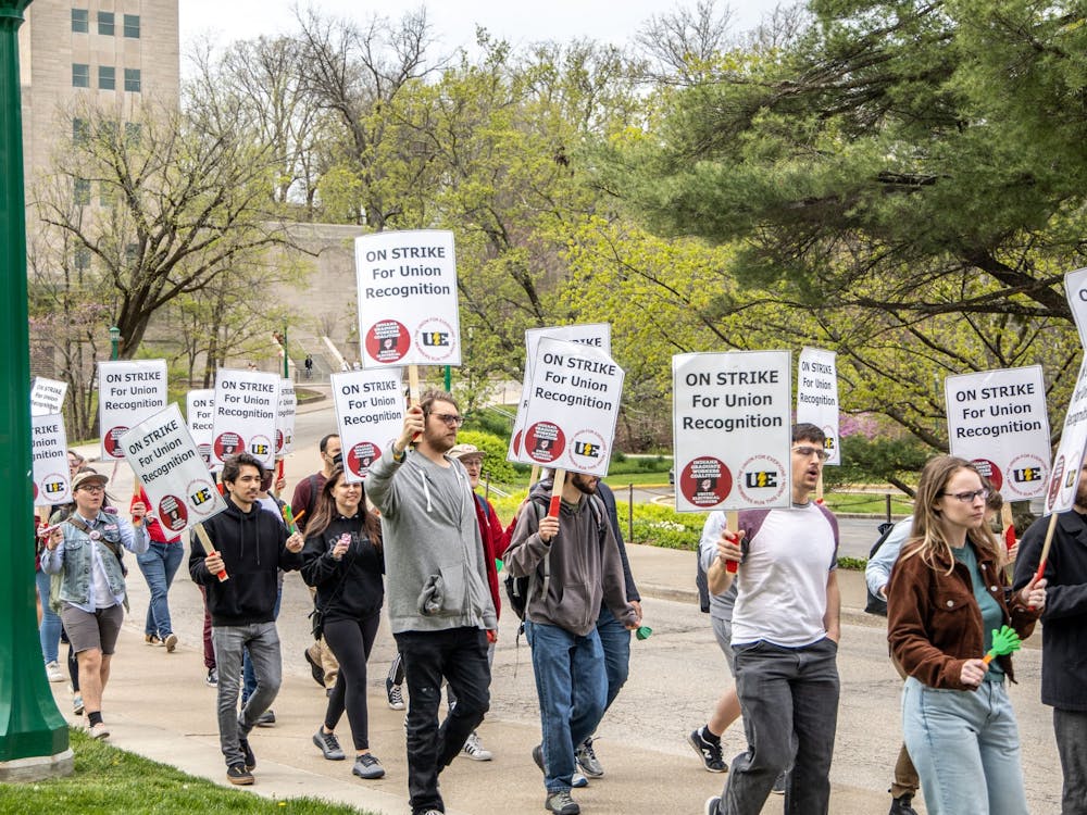 Demonstrators on one of the Indiana Graduate Workers Coalition-United Electrical Workers’ “disorientation tours” hold signs April 29, 2022, on North Forest Avenue. The organization held these tours to share its goals with prospective students, according to its Instagram account.