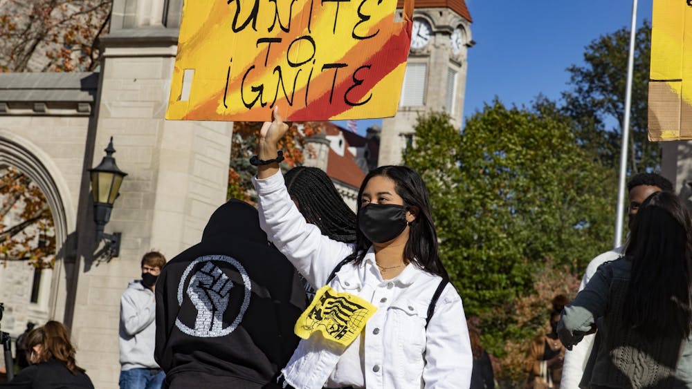 少年伊芙琳·桑切斯（Evelyn Sanchez）在10月16日的“团结点燃”拉力赛中，在样品门前举着一块牌子，上面写着“团结点燃”。她说：“多元文化学生在IUSG中没有多少代表性。”。