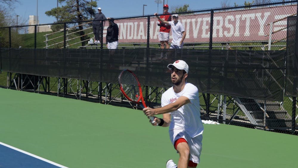 Senior Luka Vukovic kneels for a backhand at the singles match April 2, 2023, at the IU Tennis Courts. Indiana men&#x27;s tennis split its doubleheader on Sunday.