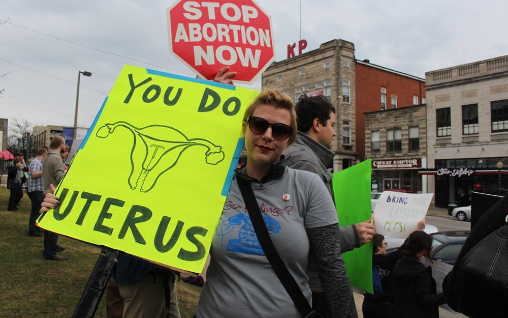 Megan Simmons, an IU grad student, holds her “You do uterus” sign, which on the back reads “Jesus never shamed women.” Simmons, a pro-choice protester, agrees with the Women’s March on Washington’s decision to officially exclude a pro-life feminist group from their website as a sponsor. 