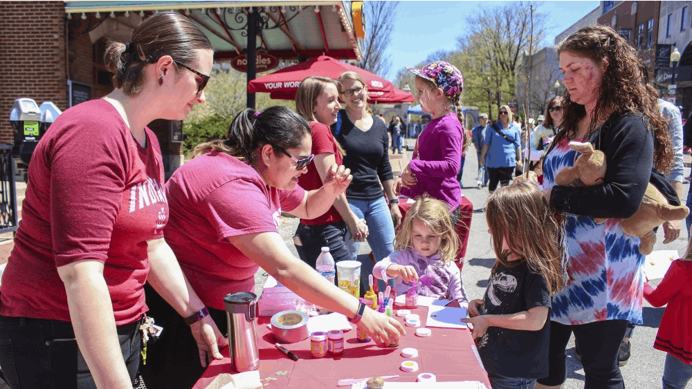 A booth for the Foundations in Science and Mathematics leads kids in an experiment with drops of paint Sunday afternoon on Kirkwood Avenue as part of the Bicentennial Street Fair. Participants would note the difference of the type of splatter from dropping the paint onto a paper from different heights.&nbsp;