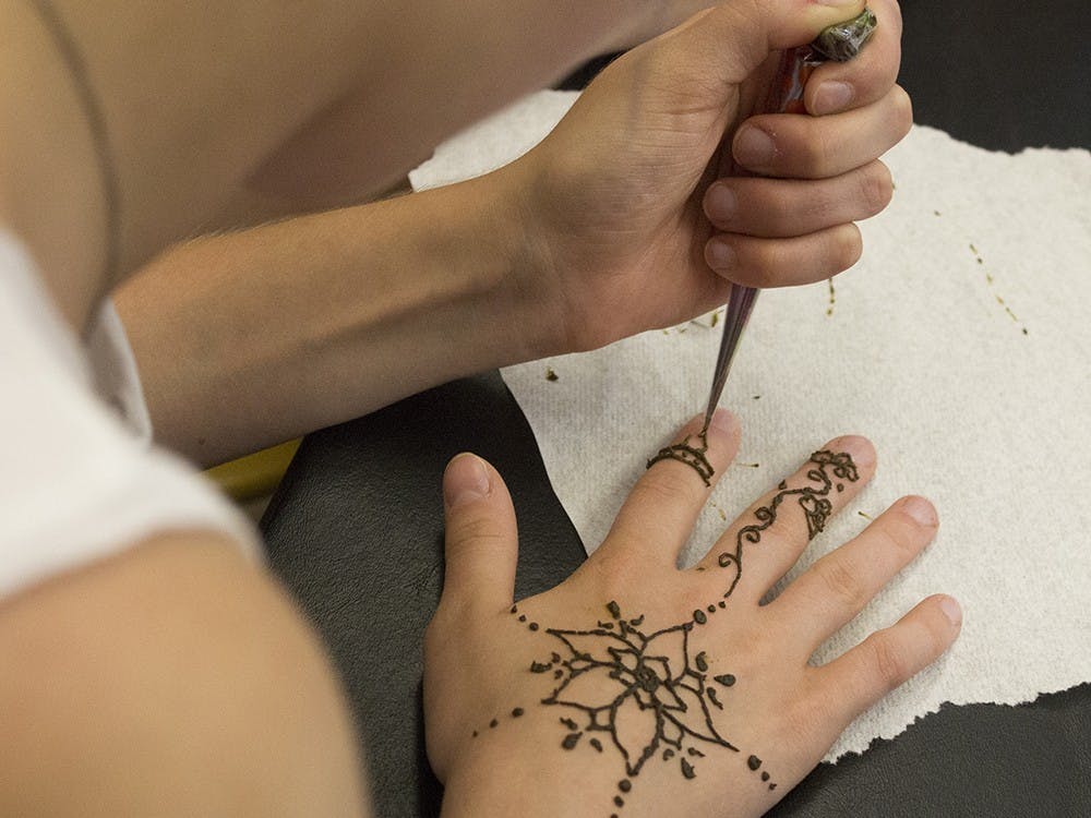 Freshman Clarissa Tokash draws a design with henna during a henna lesson at the Asian Culture Center Monday. 