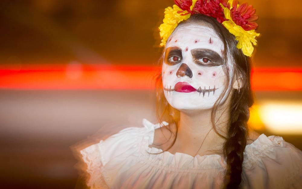 Sophomore Angelica Navarro greets students as they enter La Casa during the Dia de los Muertos event on Wednesday evening. Students in traditional dress were scattered around La Casa, Canterbury House, and the GLBT Student Support Services to provide information and background on the two-day event.