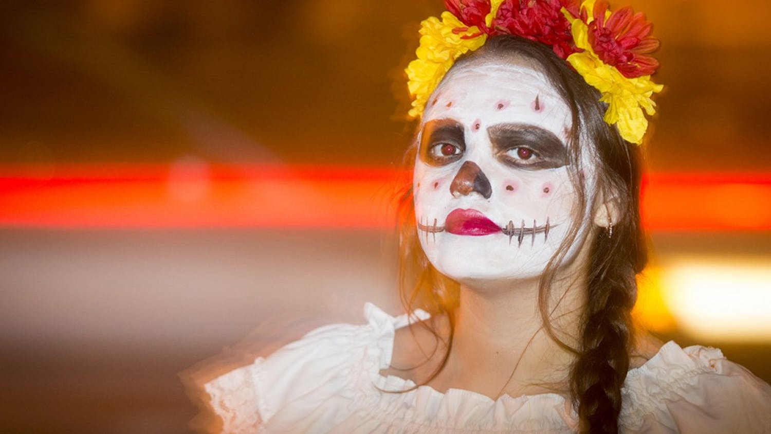 Sophomore Angelica Navarro greets students as they enter La Casa during the Dia de los Muertos event on Wednesday evening. Students in traditional dress were scattered around La Casa, Canterbury House, and the GLBT Student Support Services to provide information and background on the two-day event.