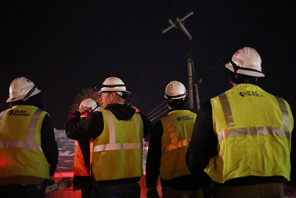 Duke Energy workers plan their coming hours of work on Monday night after a truck crashed into the side of Third Street.