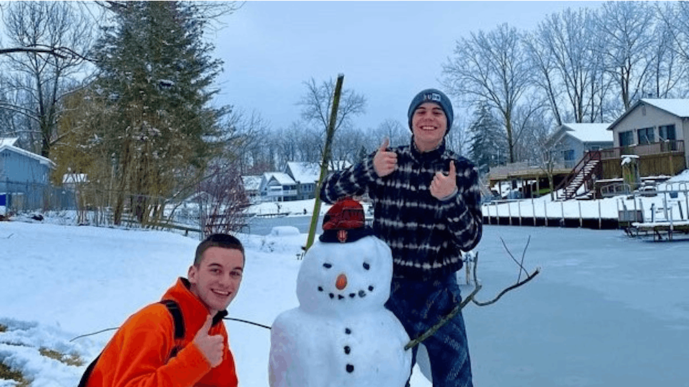 二年级学生卡森·康拉德和他的朋友和他们的雪人合影，雪人的鼻子是玉米热狗。
