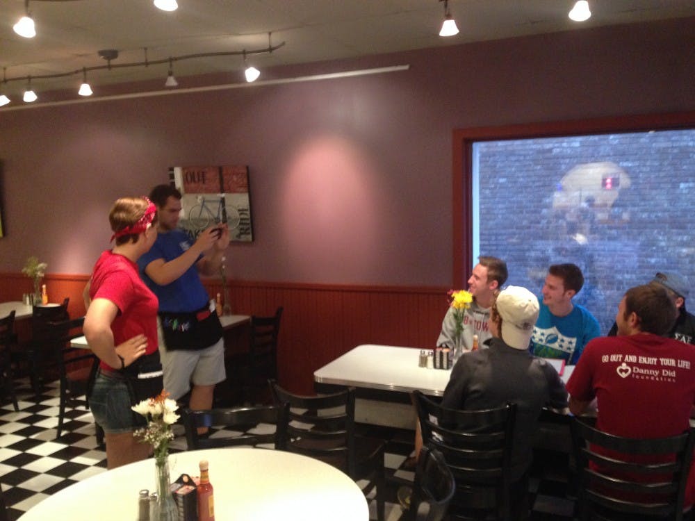 The first group of customers at the re-opening of the Village Deli gets their picture taken by waiters. 