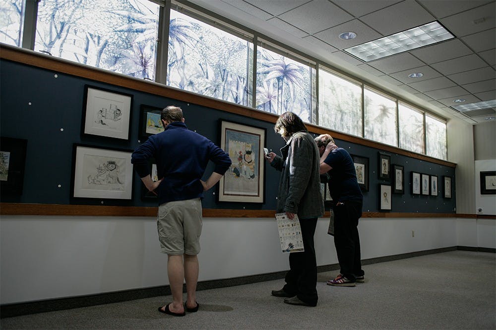 Visitors look through the 50 pieces of art displayed at the Maurice Sendak exhibition Saturday at the Monroe County Public Library. Sendak was well known for his drawings of Where the Wild Things Are.