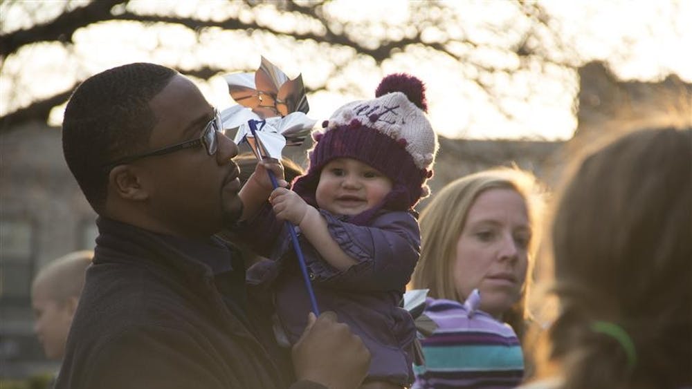 A man holds his daughter while listening to speakers at the anti-child abuse event at the Monroe County Courthouse last night. Pinwheels were distributed for the children to play with and to raise awareness about child abuse.  The event was held in honor of National Abuse Prevention Month.  