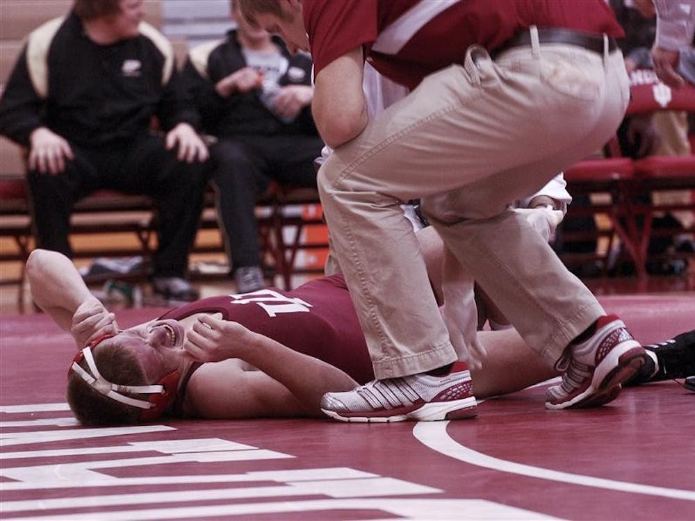Redshirt freshman Taylor Walsh lies on the mat with a knee injury Sunday at University Gym. Walsh resumed wrestling but lost to Purdue's Ivan Lopouchanski 10-4.