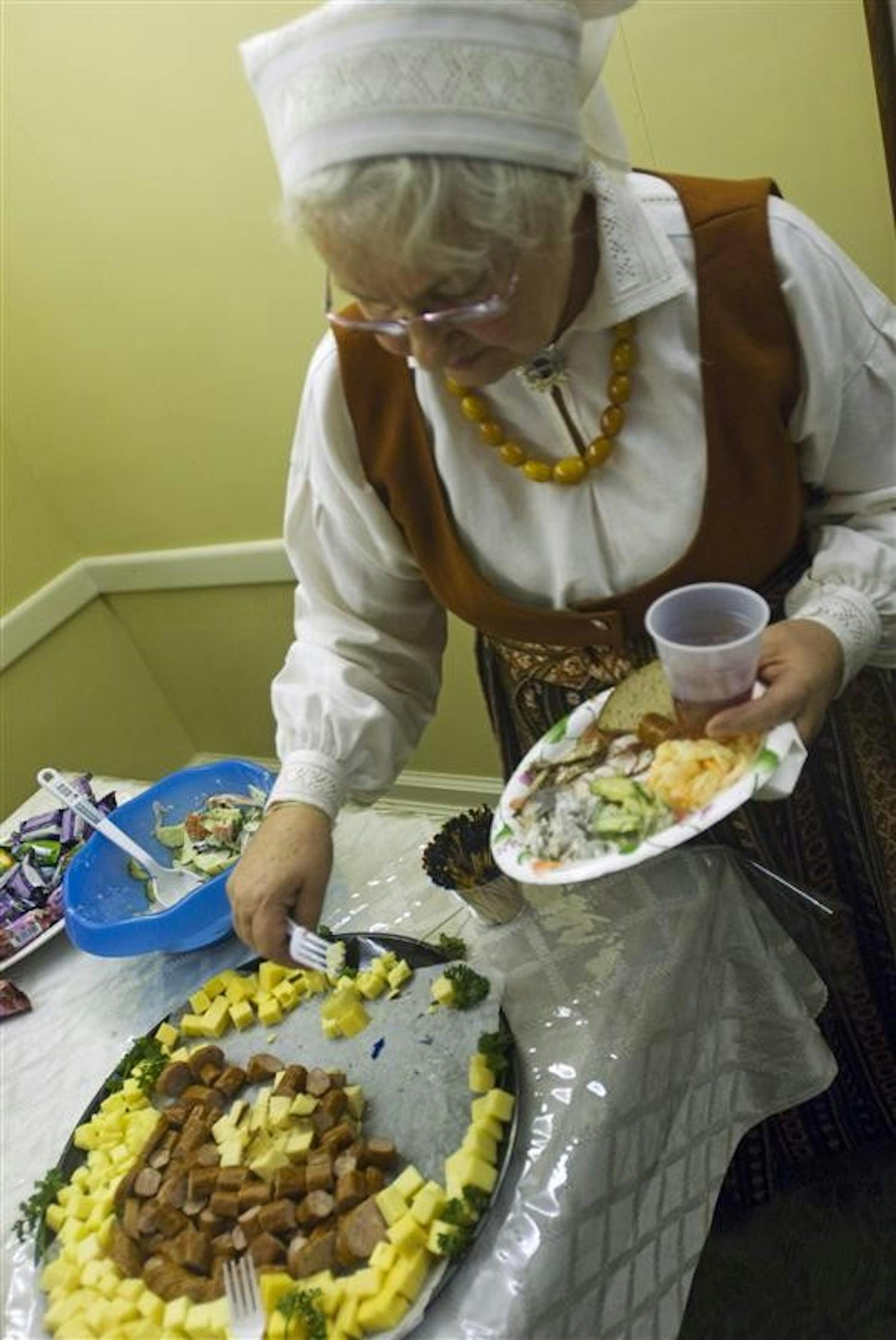 IU alumnus Skaidrite Hatfield who moved from Latvia in 1950 and graduated from IU in 1959 dishes out a meal during a Latvian Indepence Day celebration Thursday night in the IMU Faculty Club. Hatfield is adorned in a historic outift traditionally worn in the region of Zemgale, Latvia.