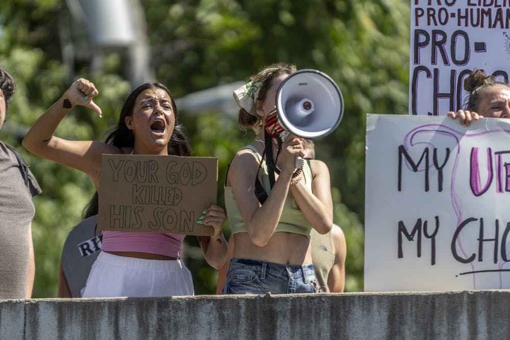 Protestors lead chants behind Women’s Care Center on June 27, 2022, on College Avenue. The Party for Socialism and Liberation organized Monday's protest and claims the center is set up to dissuade people from having abortions.