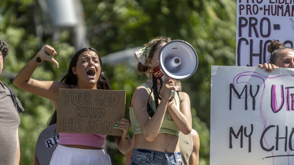 Protestors lead chants behind Women’s Care Center on June 27, 2022, on College Avenue. The Party for Socialism and Liberation organized Monday's protest and claims the center is set up to dissuade people from having abortions.