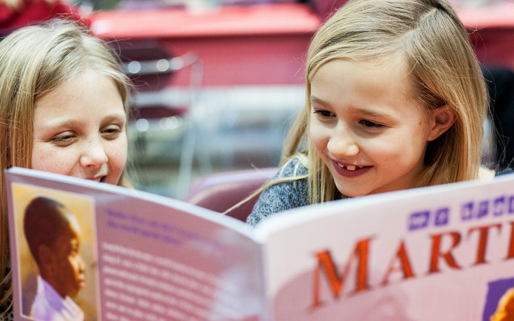 Two elementary-age girls read a book about Martin Luther King Jr. at the MLK Birthday Celebration. The community teach-in, for both children and their families, took place Sunday&nbsp;in the IU School of Education. The celebration included coloring activities, a musical performance, an interactive discussion and a celebratory birthday cake.