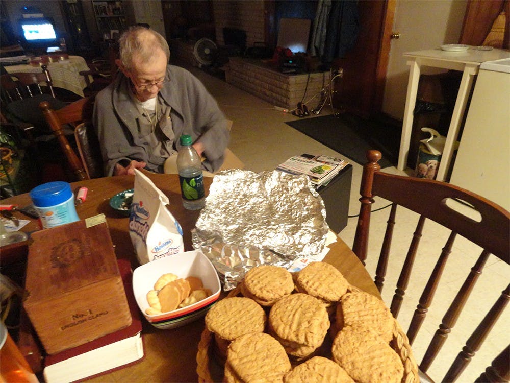 George McNeely thumbs through a dictionary after examining a basket of several dozen peanut butter cookies.  The cookies are a family recipe that was originally created by his mother.
