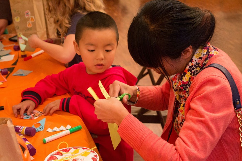 Luming Xu helps her son Yoyo cut out teeth for a monster bookmark at the Mathers Museum's Halloween Family Fun Fest on Oct. 26.